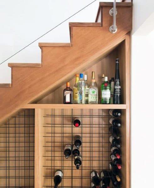 Under-stair wine storage with wooden shelves, metal racks, and liquor bottle display