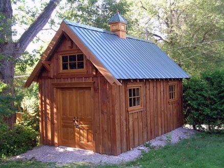 Small wooden shed with a metal roof and rustic design, nestled in a wooded backyard.