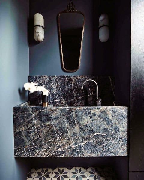 Modern bathroom with dark marble sink, mirror, and sleek wall lighting.