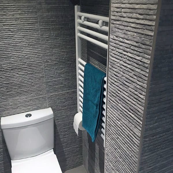 Modern bathroom with textured grey walls, a toilet, and a towel on a heated rack