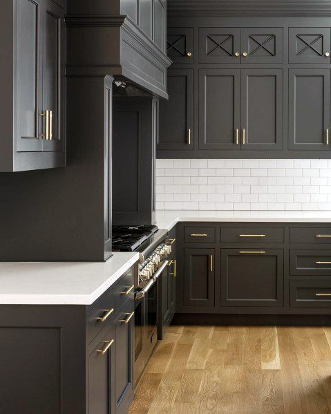 Stylish kitchen with dark gray cabinetry, white subway tile backsplash, and light hardwood flooring