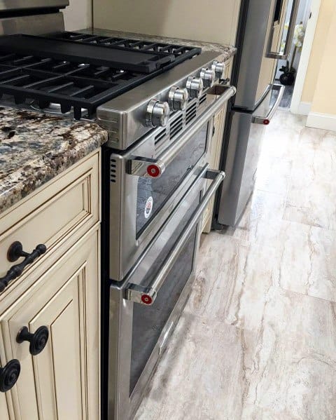 Stainless steel gas oven and refrigerator with beige cabinets and light ceramic flooring