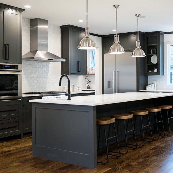 A contemporary kitchen featuring dark cabinets, sleek pendant lights above the island, and wooden stools for a stylish yet functional space