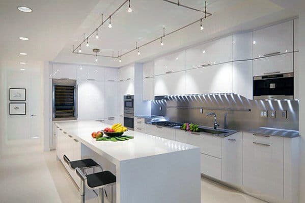 Sleek white kitchen with modern track lighting above the island, creating a bright, functional, and minimalist space