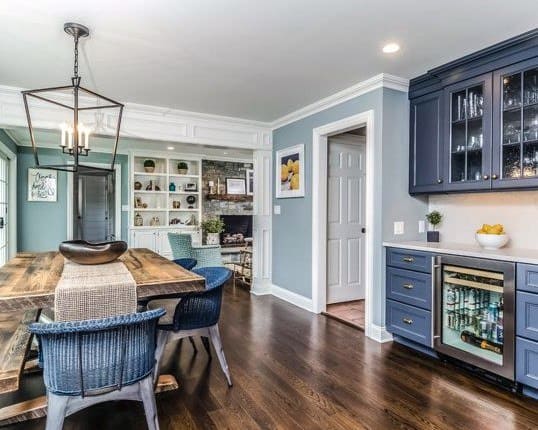 Charming kitchen mini bar with navy blue cabinets, a beverage cooler, and glass storage.