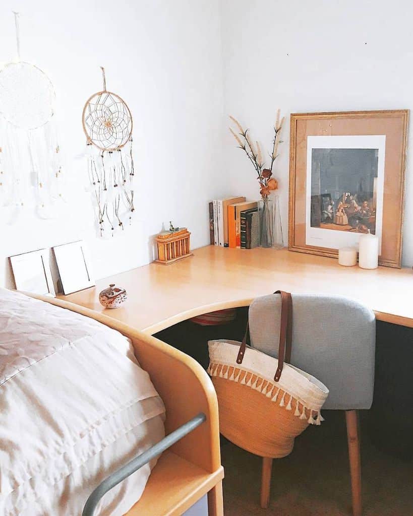 Cozy corner desk with decor, dreamcatchers, and books in a minimalist bedroom setup.