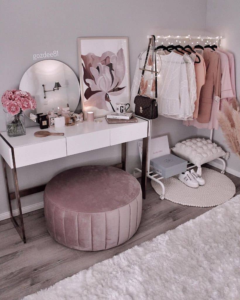 Vanity with pink stool, clothes rack, and decor in a soft, feminine bedroom setup.