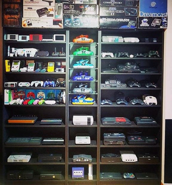 Shelves displaying a collection of various gaming consoles and controllers, organized by type and brand