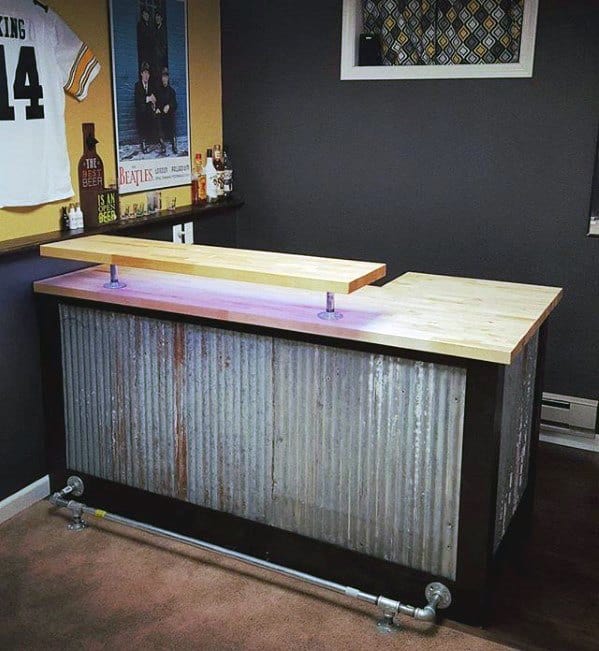 DIY industrial bar with corrugated metal siding, wooden countertop, and sports memorabilia on the wall.