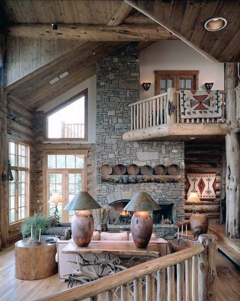 Modern rustic living room with a stone fireplace, elegant furniture, and large windows showcasing nature