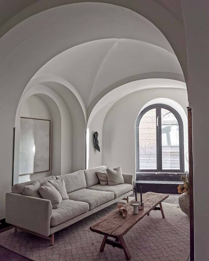 Arched minimalist living room featuring a neutral sofa, rustic wooden coffee table, and Wabi-Sabi elements