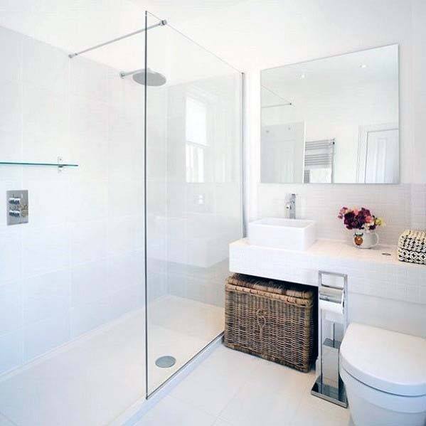 Modern white bathroom with a glass shower, square sink, wicker basket, and a vase of flowers on the counter