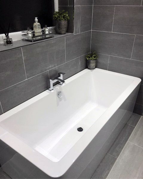 Modern bathroom with a white bathtub and grey tiled walls