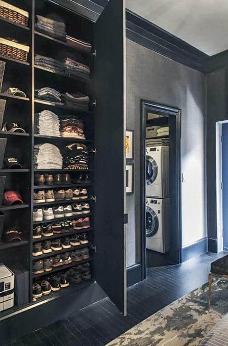 Closet with folded clothes, shoes, and hats beside a door leading to a laundry room with stacked washer and dryer