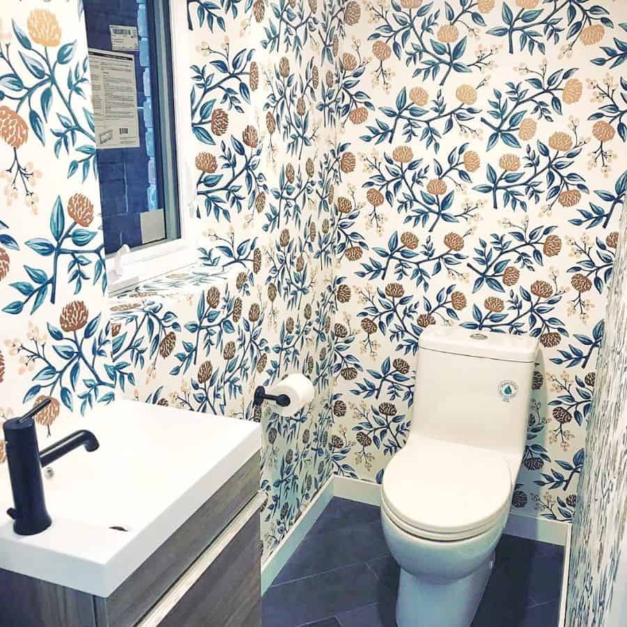 Bathroom with floral wallpaper, white toilet, black faucet, and small window