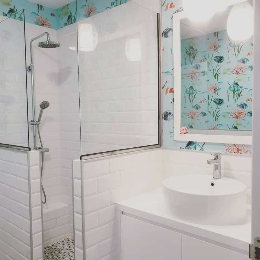 Bright bathroom with floral wallpaper, glass shower, and circular sink on a white vanity