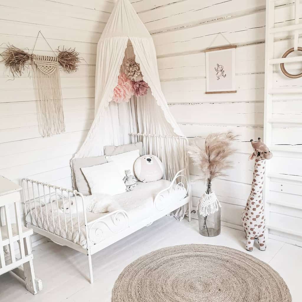 Cozy nursery with a white crib, airy canopy, giraffe toy, pampas grass, and a round rug on wooden floor