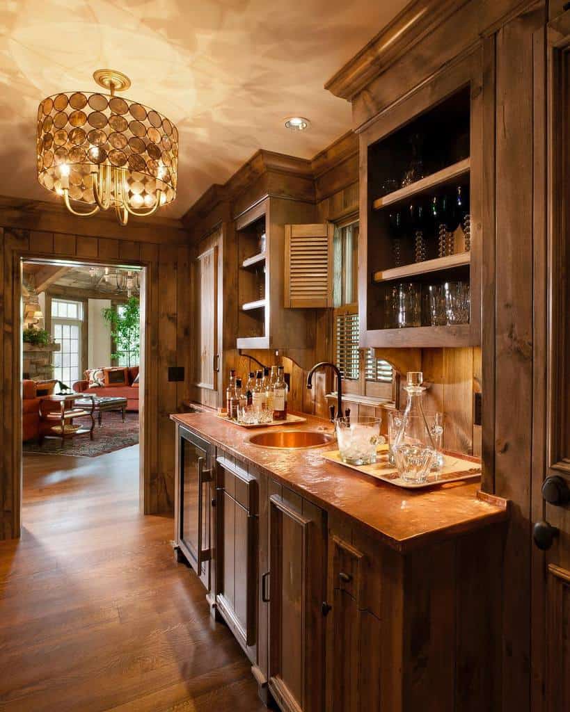 Cozy rustic wet bar featuring wooden cabinetry, a copper countertop, and warm ambient lighting.