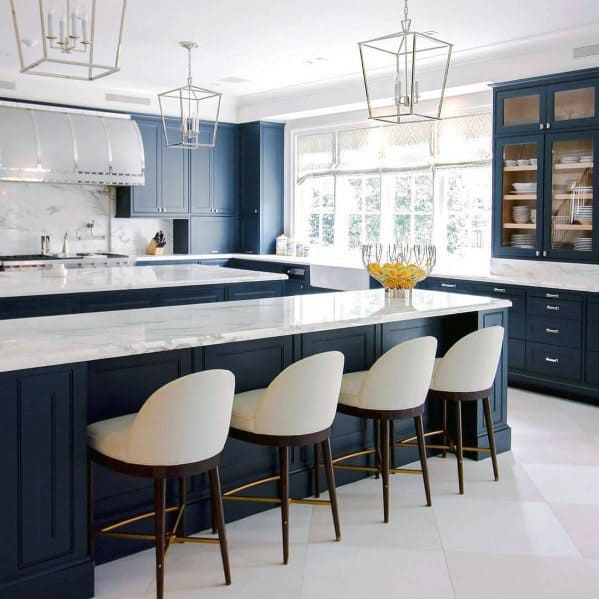 Elegant kitchen with navy blue cabinets, white marble countertops, and white and beige tile flooring