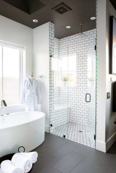 Contemporary bathroom with freestanding bathtub, large glass shower, and subway tile walls.