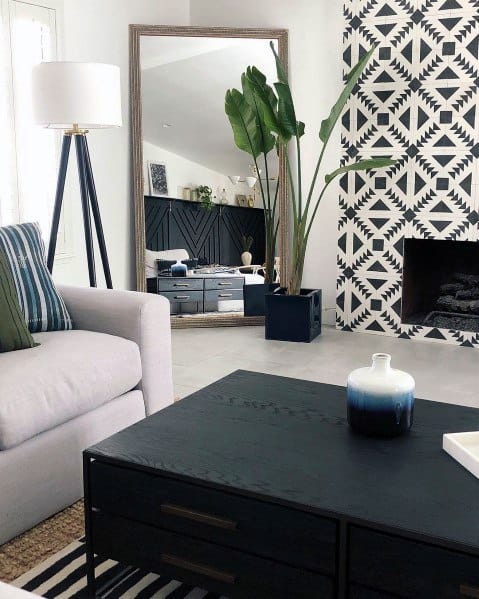 A stylish living room featuring a fireplace with bold black-and-white patterned tiles, complemented by modern furnishings and greenery.