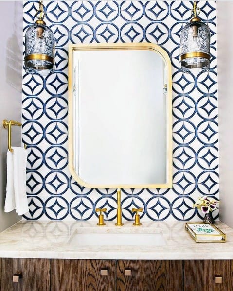 Blue and white patterned tile backsplash with gold framed mirror and brass fixtures.