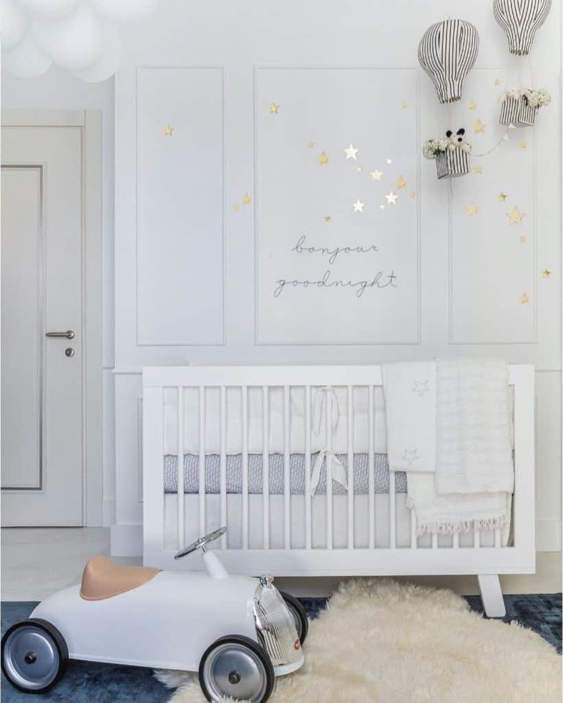 White baby room with star wall decals, a crib, and a vintage toy car on a soft rug.