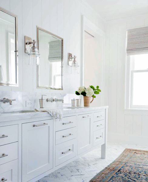 Bright white bathroom with double vanity, mirrors, and a window illuminating the space flawlessly