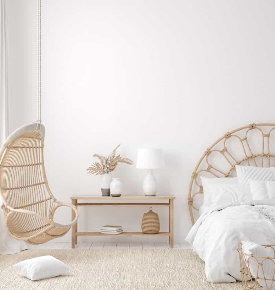 Minimalist boho bedroom with a natural wicker swing chair, a rattan headboard, and neutral decor.