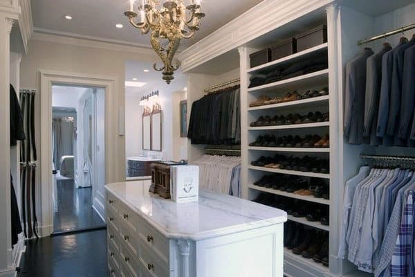 Spacious walk-in closet with a chandelier, marble-topped island, and neatly organized clothes and shoes on shelves