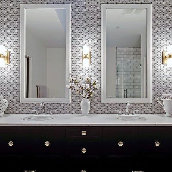 Bathroom with hexagon tiles, modern vanity, and elegant mirrors with gold sconces.