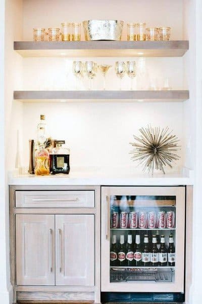 Elegant white mini bar with open shelving, a beverage fridge, and stylish decor accents.