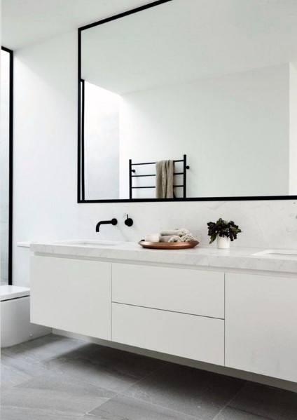 Minimalist white bathroom with large mirror and floating vanity with marble countertop.