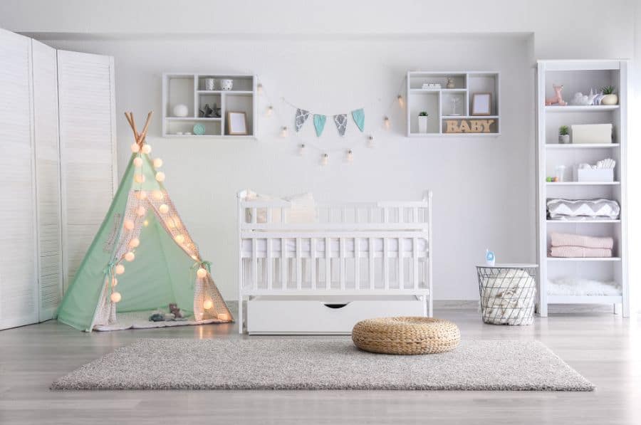 Baby room with white crib, mint green tipi tent with string lights, soft rug, and storage shelves.