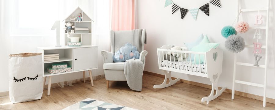 Cute baby room with rocking cradle, cozy armchair, and pastel decor accents.