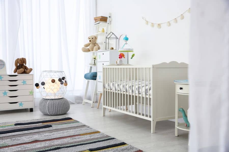 Bright and playful nursery with a white crib, star-themed dresser, and colorful rug.