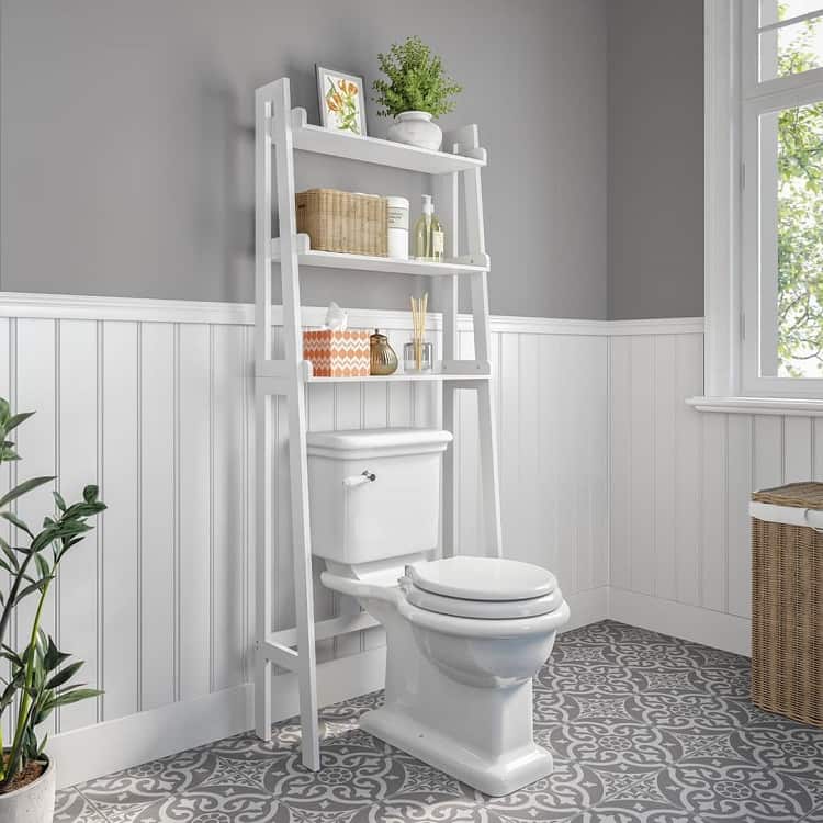 Bathroom with white over-the-toilet shelving, patterned gray floor tiles, and wall paneling.