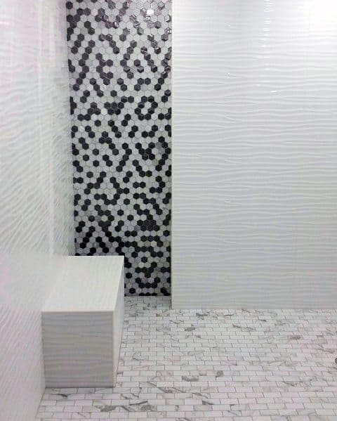 Modern shower with textured white walls, black and white hexagon accent, and built-in seat.