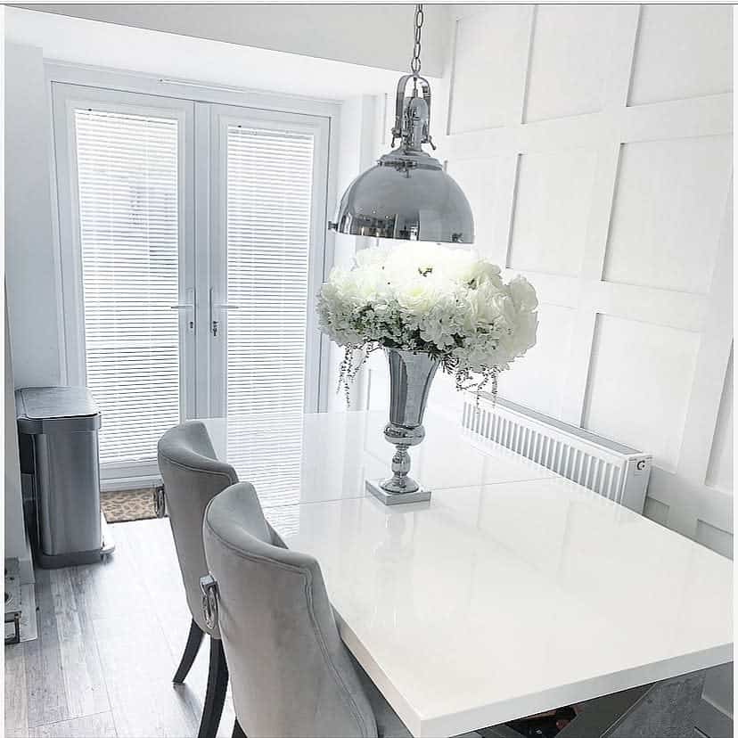 white wall paneling dining room silver vase of flowers white table 