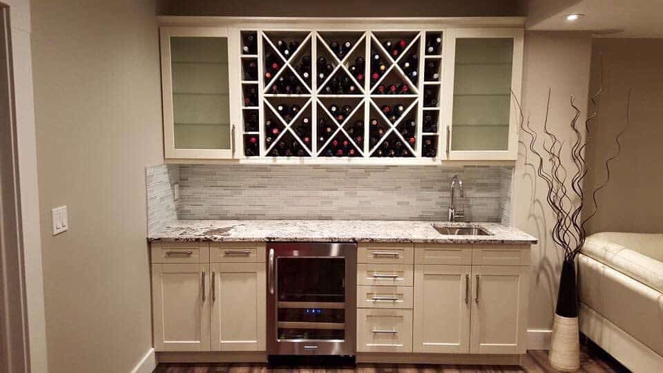 Contemporary wet bar with wine storage, glass-front cabinets, mosaic backsplash, and granite countertop.