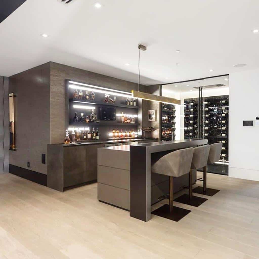 Sleek modern wet bar with illuminated shelves, minimalist design, and adjacent glass-enclosed wine room.