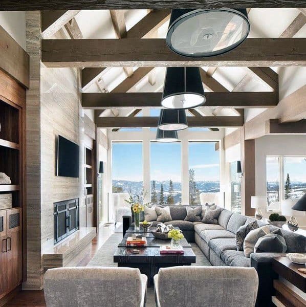 Spacious living room with large sectional sofa, wooden beams, modern lighting, and a snowy mountain view through windows