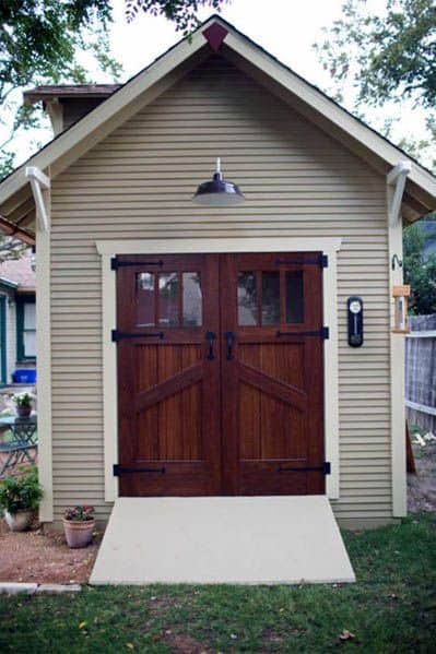 Barn-style shed with wooden double doors, outdoor lantern, and a small entry ramp.