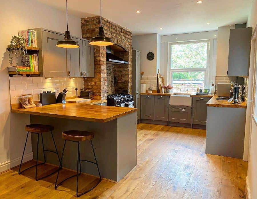 rustic kitchen gray cabinets brick feature wood bar two stools