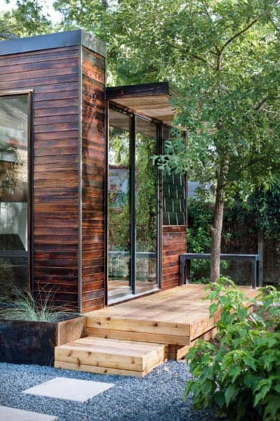 Contemporary wood office shed with sliding glass door and wooden deck steps.