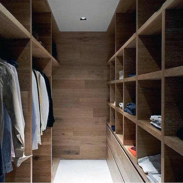 Wood-paneled walk-in closet with clothes hanging on the left and folded on shelves to the right