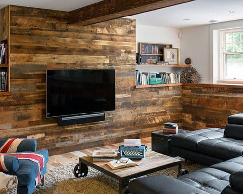 Cozy home theater with rustic wood-paneled walls, leather seating, and a wall-mounted TV.