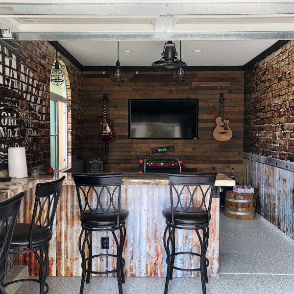 Industrial-style garage bar with corrugated metal, wooden walls, guitars, and black bar stools.