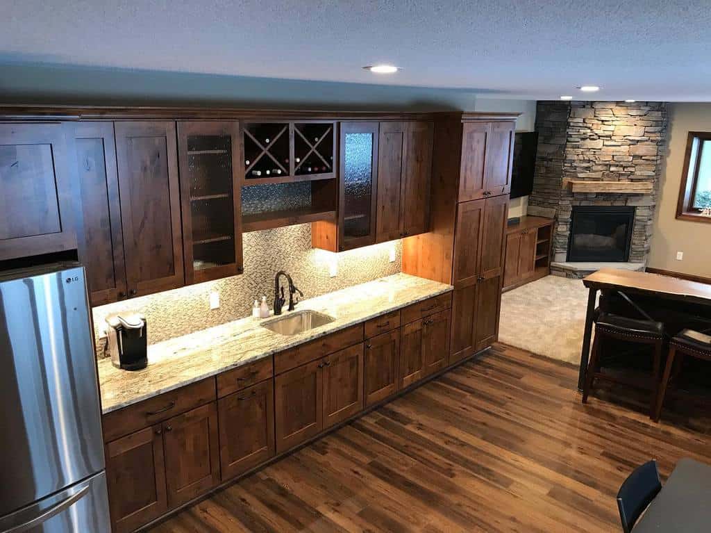 Warm and inviting wooden wet bar with rich cabinetry, granite countertops, and subtle backsplash lighting.