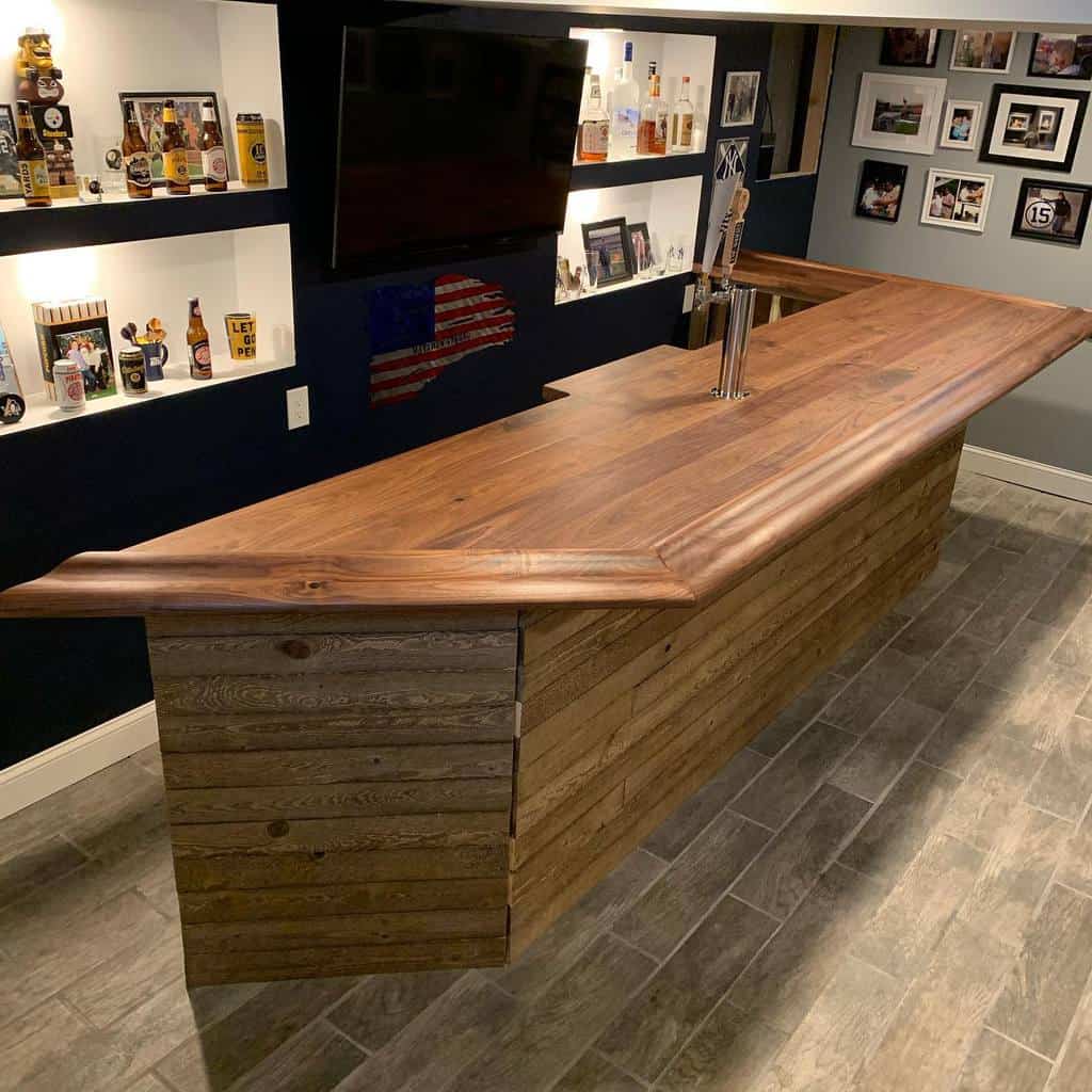 A rustic wood wet bar featuring a polished countertop and illuminated display shelves.